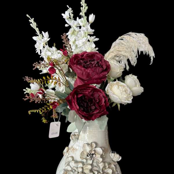 Floral arrangement with burgundy and white blooms in a decorative ceramic vase