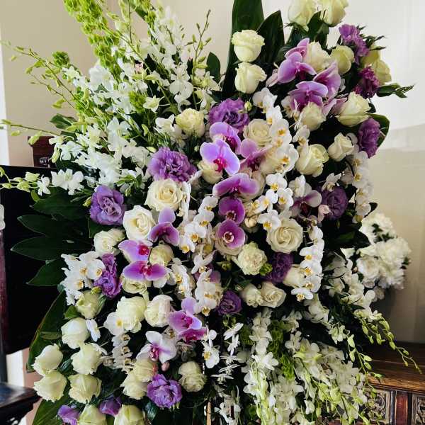 Large standing floral spray with white and purple flowers on an easel