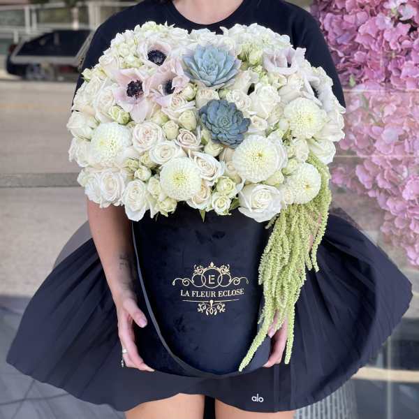 Large bouquet of white and pale pink flowers with blue succulents in a black box