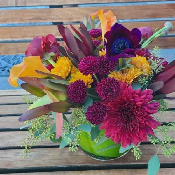 Colorful mixed bouquet in a glass vase on a wooden table