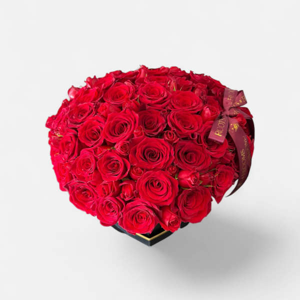 Heart-shaped bouquet of red roses with a ribbon on a black box