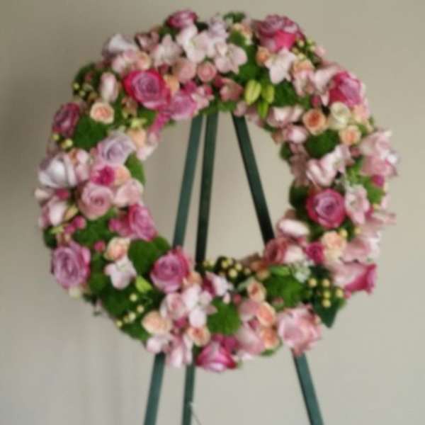Pink and white floral wreath on a green easel