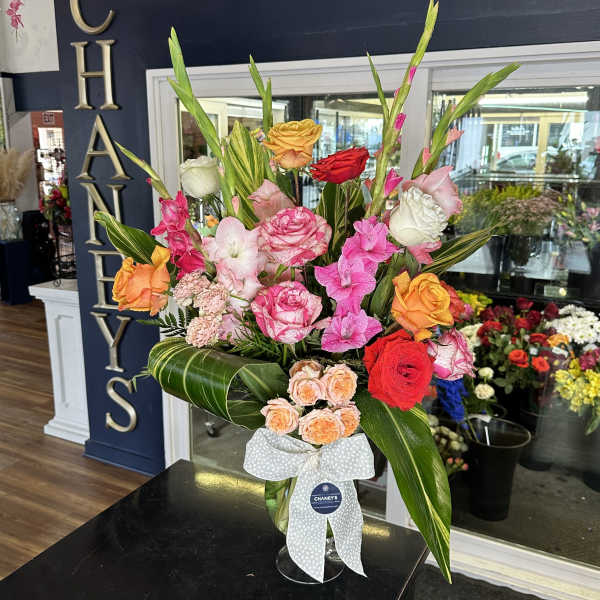 Tall mixed bouquet of pink, red, orange, and white roses in a glass vase