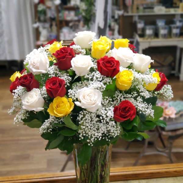 Bouquet of red, white, and yellow roses in a clear glass vase