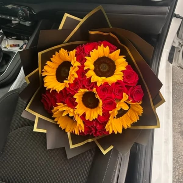 Bouquet of red roses and yellow sunflowers wrapped in dark paper