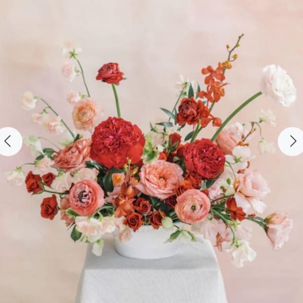 Pink and red floral arrangement in a white bowl vase
