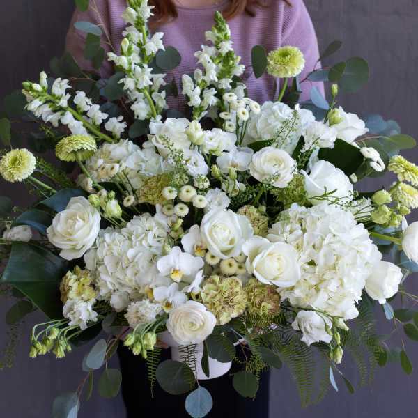 Large white floral arrangement with roses and hydrangeas