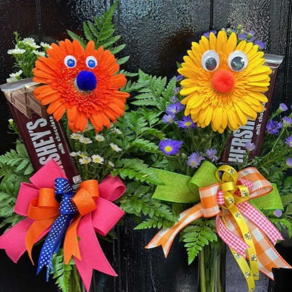 Two novelty flower arrangements with smiling faces in glass vases