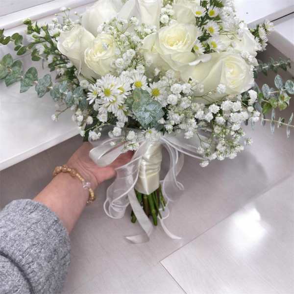 White rose bouquet with baby's breath and daisies tied with a satin ribbon