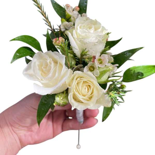 White rose boutonniere with small blossoms and glossy leaves