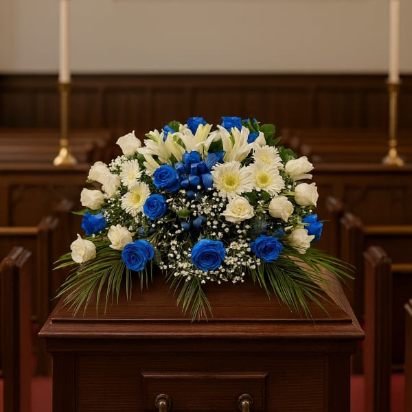 Blue and white floral spray on a wooden casket in a church