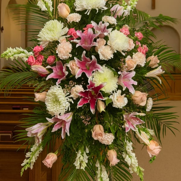 Large pink and white funeral spray with lilies and roses in a church