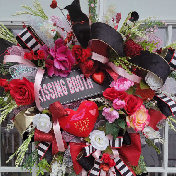 Heart-shaped floral wreath with red and pink roses and a "Kissing Booth" sign