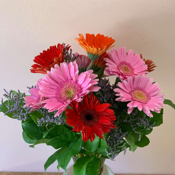 Bouquet of pink, red, and orange gerbera daisies in a glass vase