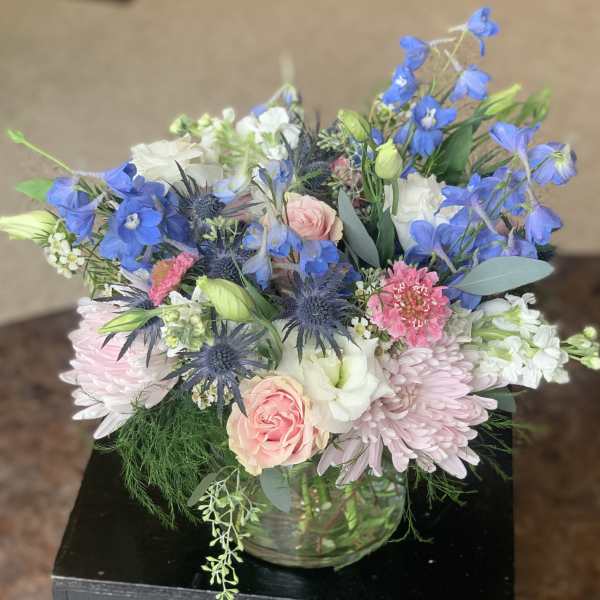 Mixed bouquet of blue, pink, and white flowers in a glass vase