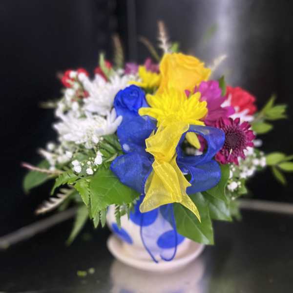 Colorful bouquet in a white vase with blue and yellow ribbon