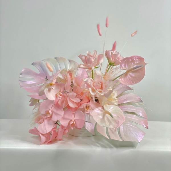 Pink and white orchid arrangement in a low container