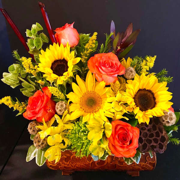 Bright bouquet with sunflowers and orange roses in a carved wooden container