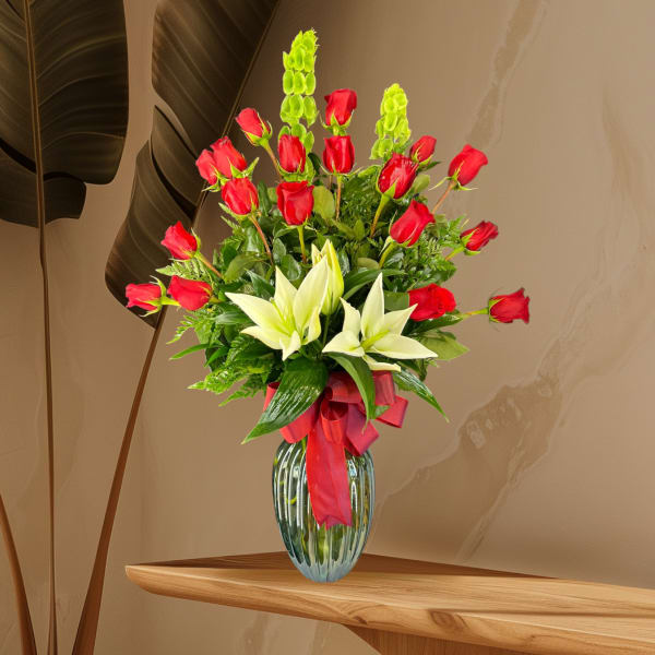 Red roses and white lilies in a glass vase with a red ribbon