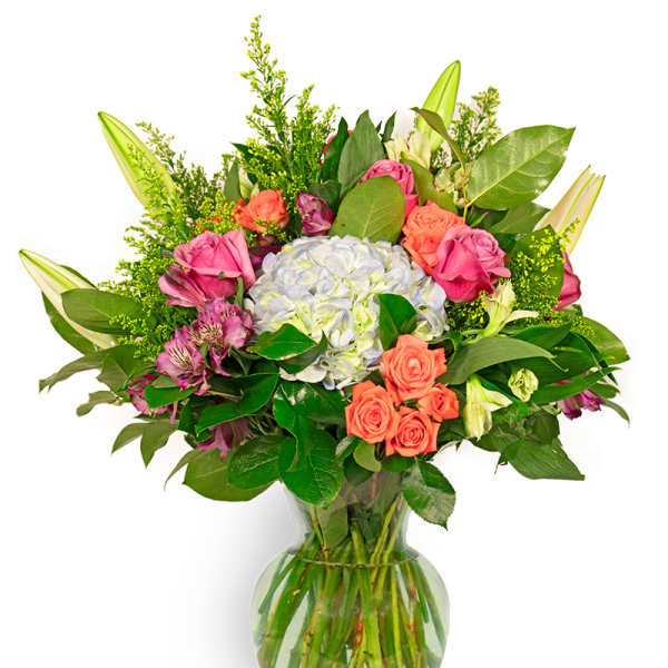 Tall mixed bouquet with blue hydrangea, pink and orange roses, lilies, and alstroemeria in a clear glass vase