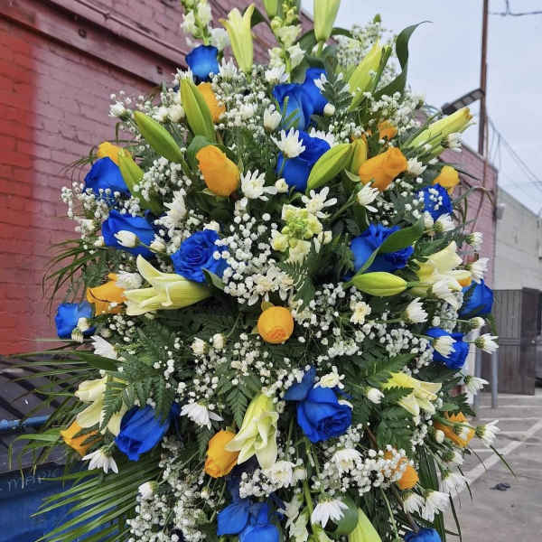 Large standing floral spray with blue and yellow roses and white lilies