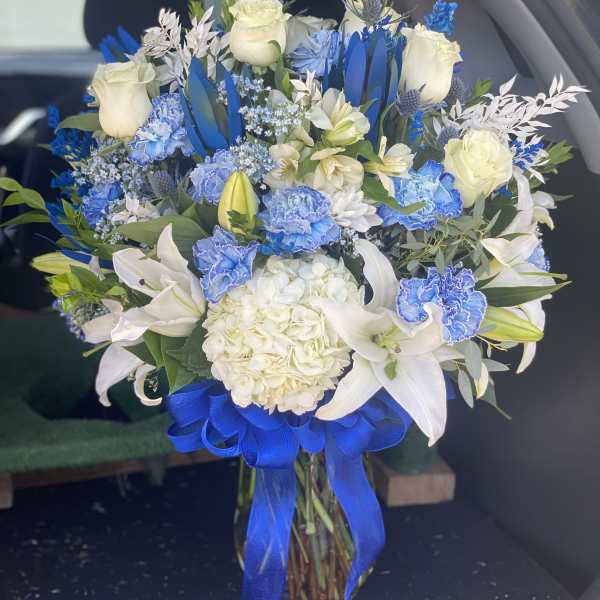 Blue and white bouquet with roses, lilies, and hydrangea tied with a blue ribbon