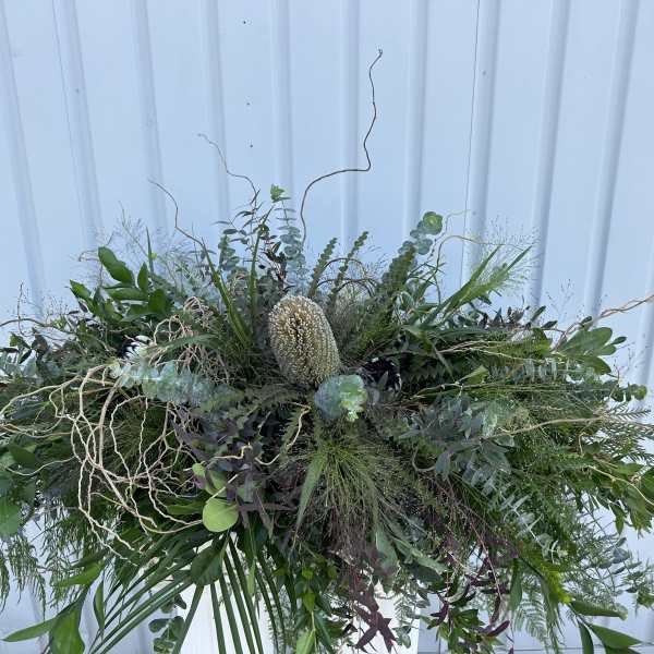 Large greenery arrangement with a central cream protea-like bloom