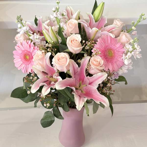 Pink lilies, roses, and gerbera daisies in a pink vase