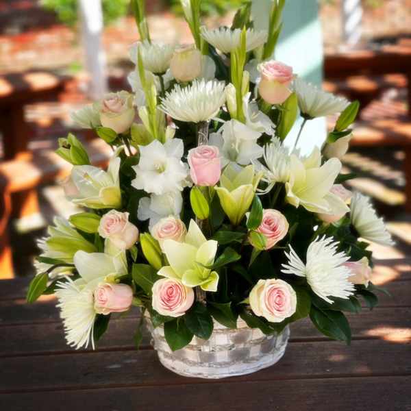 Pink roses and white lilies arranged in a clear glass bowl