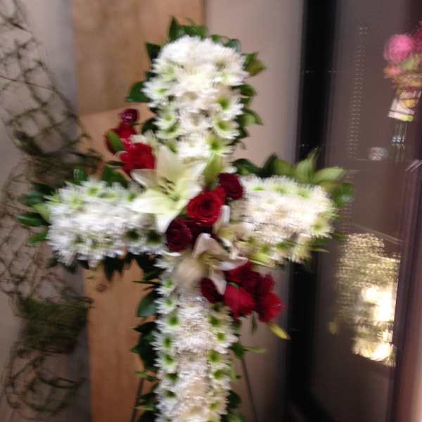White floral cross with red roses on a stand