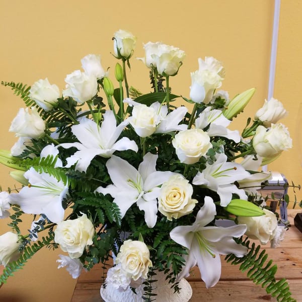 White lilies and roses arranged in a white vase