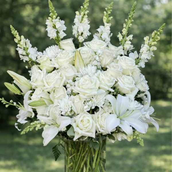 White roses and lilies arranged in a clear glass vase