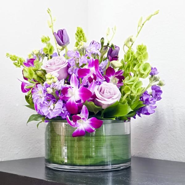 Purple and pink flowers arranged in a clear glass vase