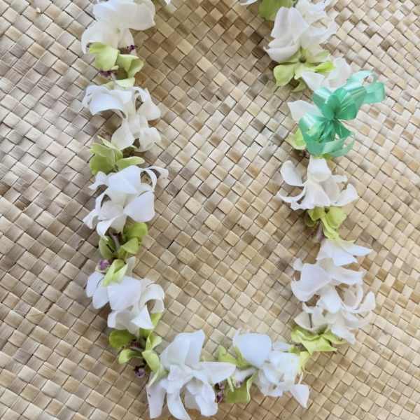 White and green flower lei on a woven mat