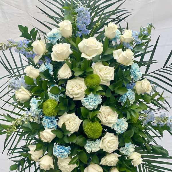 White roses with blue carnations and green pompons in a standing spray