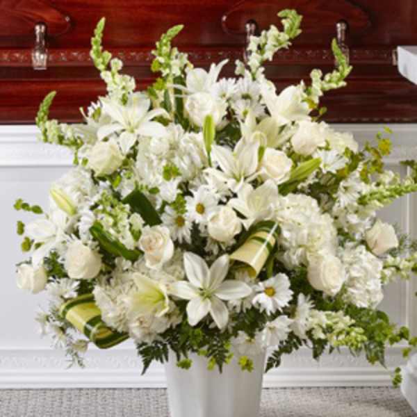 White floral arrangement in a white vase with lilies and roses