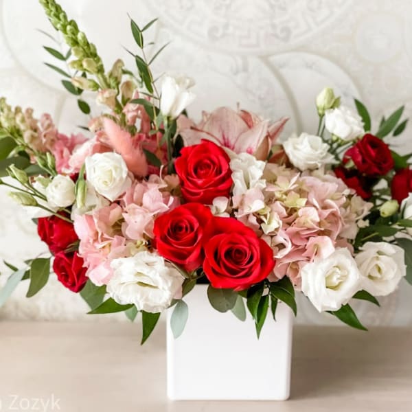 Red and white roses with pink blooms in a white vase