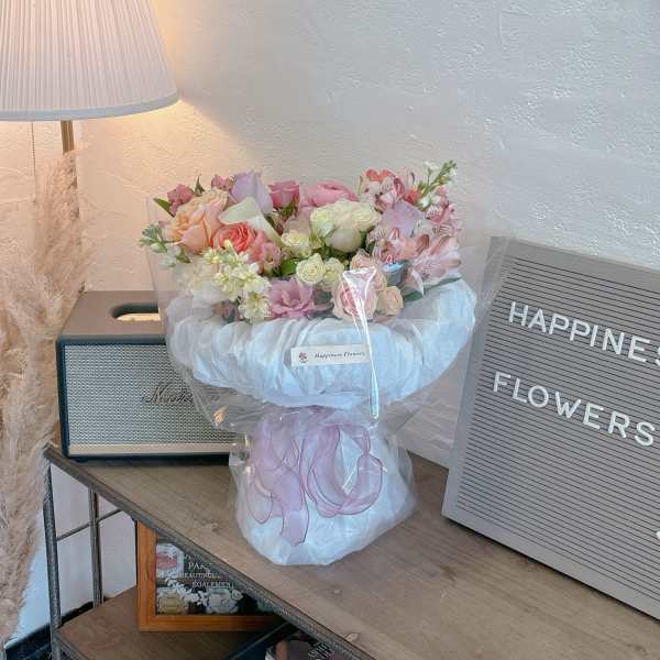 Pastel bouquet of roses and alstroemeria wrapped in white tulle