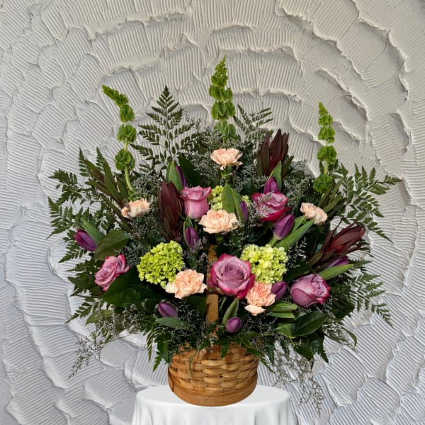 Basket arrangement of pink roses, tulips, carnations, and green hydrangeas