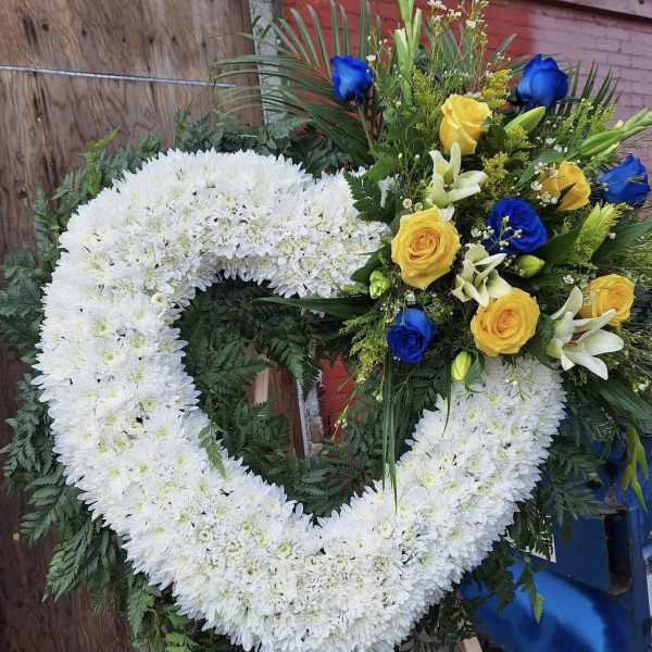 Heart-shaped white floral wreath with yellow and blue roses