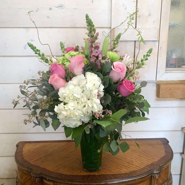 Pink roses and white hydrangea in a tall glass vase