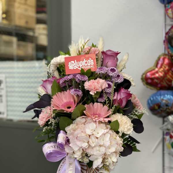 Pink and white mixed bouquet in a patterned vase with a lavender ribbon