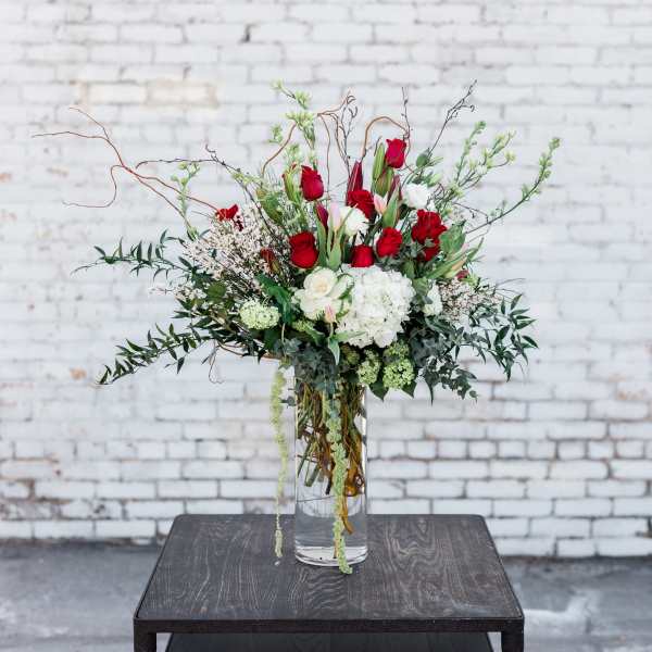 Tall bouquet of red and white flowers in a clear glass vase