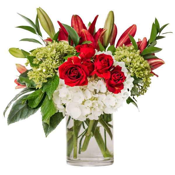 Red roses, red lilies, and white hydrangeas arranged in a clear glass cylinder vase