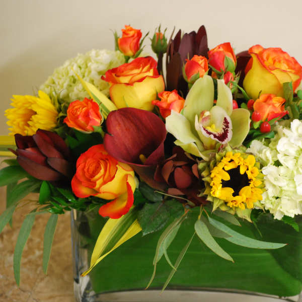 Mixed floral arrangement in a glass vase with orange roses and white hydrangeas