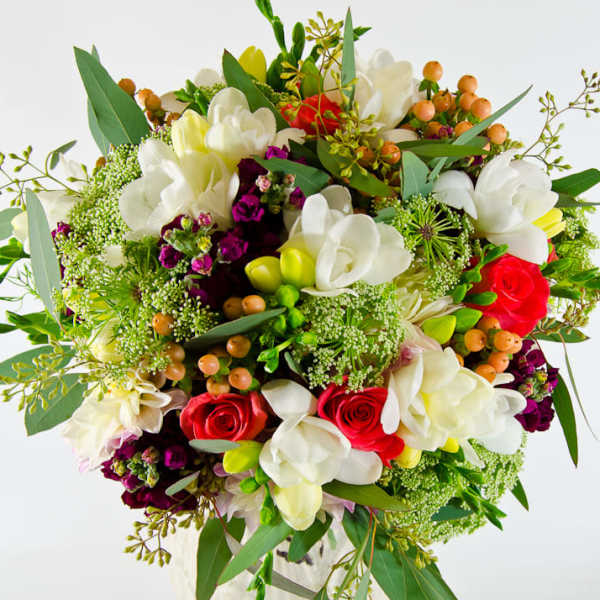 Bouquet of white orchids and red roses with mixed greenery