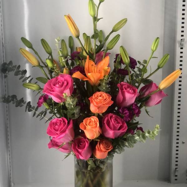 Pink and orange roses with lilies in a glass vase