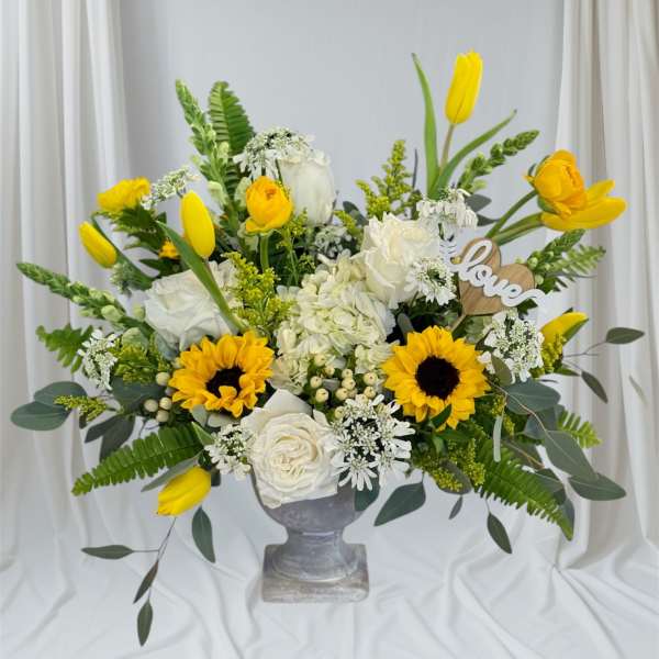 Yellow tulips and white roses arranged in a gray vase