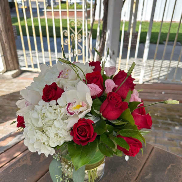 Bouquet of red roses, white hydrangea, and white orchids in a glass vase