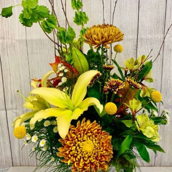 Yellow lilies and chrysanthemums in a glass vase with tall branches
